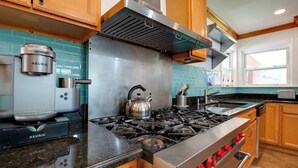 Une cuisine moderne équipée d’une cuisinière en acier inoxydable, d’une bouilloire et d’une machine à café Keurig.