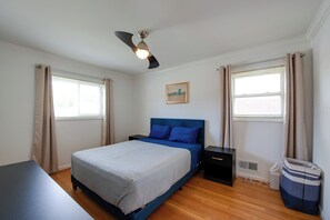 Ein Schlafzimmer mit einem Bett, einem Nachttisch, einem Deckenventilator und einem Fenster mit Vorhängen.