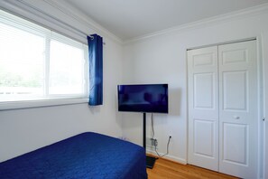 Une pièce avec un lit, un téléviseur fixé au mur et une porte.