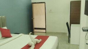 A hotel room with a bed, a chair, a desk, and a television. - Sakas Manor Guest Rooms (Hyderabad)