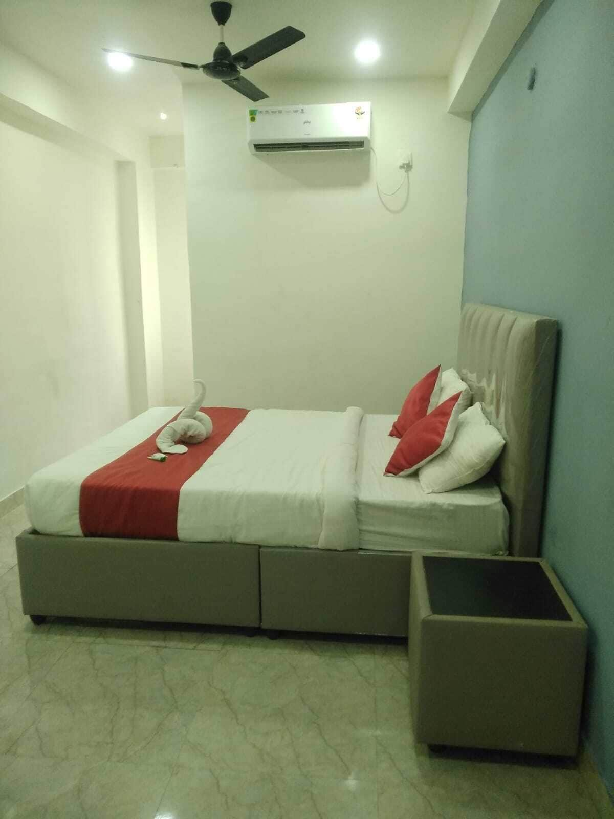 Un dormitorio con cama, una mesita de noche, un ventilador de techo y un equipo de aire acondicionado.