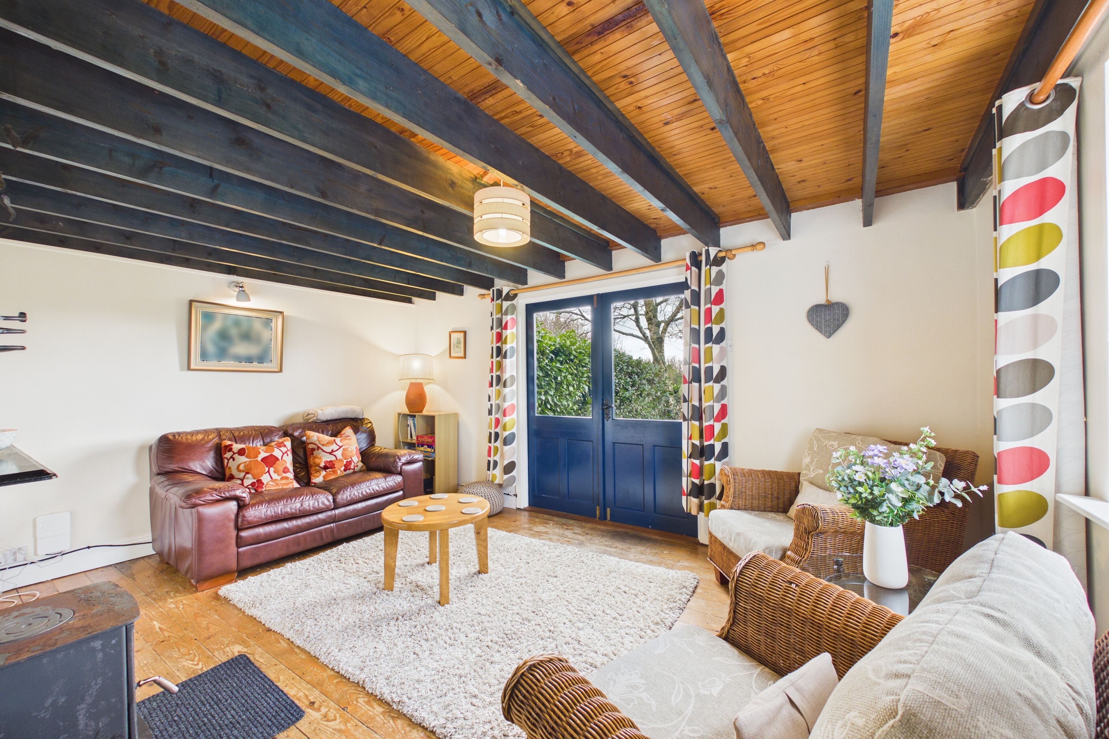 A cozy living room with a leather sofa, a wooden coffee table, and a wicker chair.