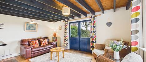 A cozy living room with a leather sofa, a wooden coffee table, and a wicker chair.