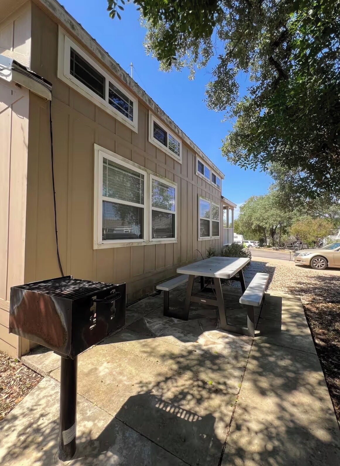 Un espace extérieur aménagé avec un barbecue, une table et des bancs.