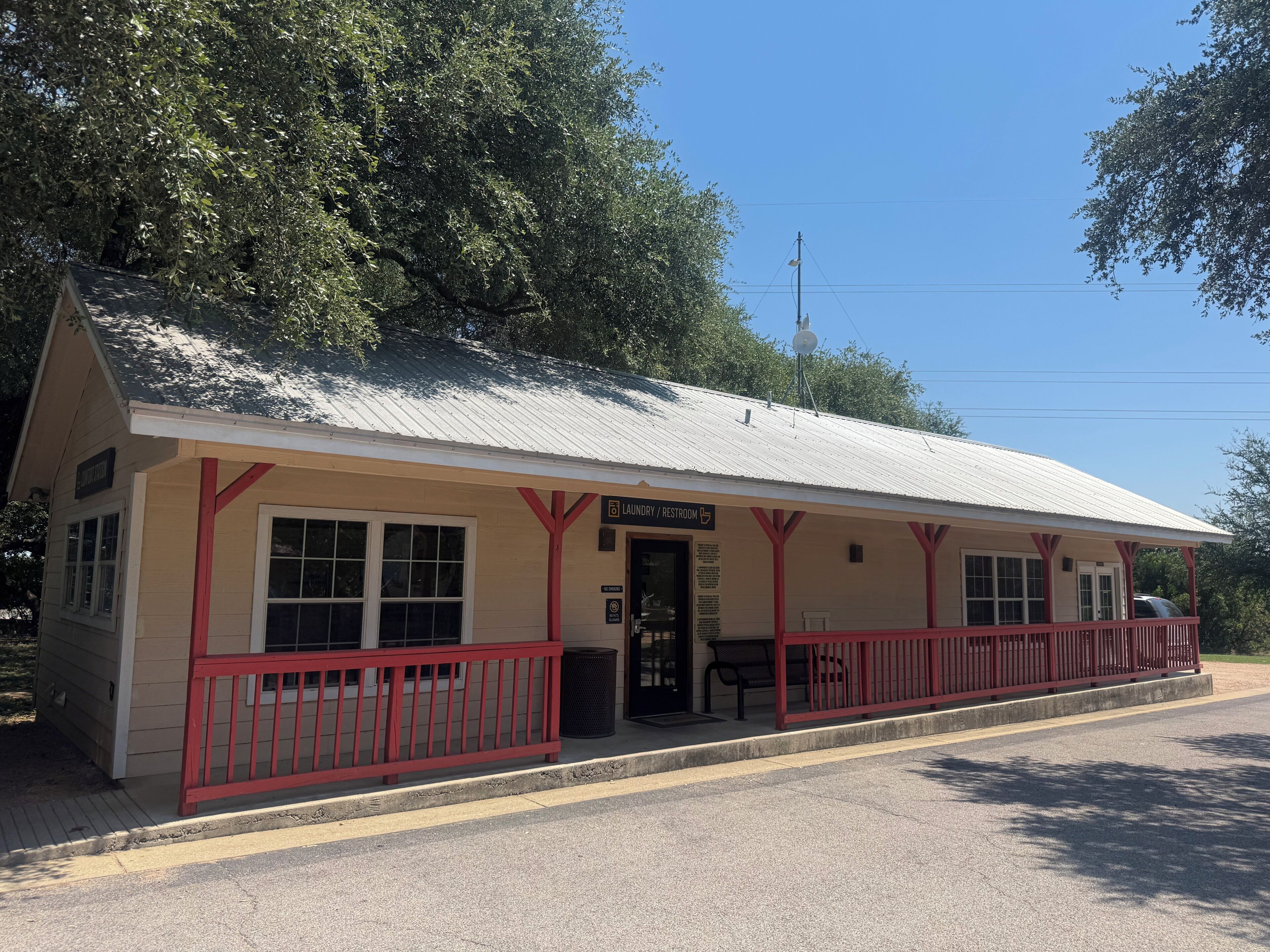 A small building with a red railing, a sign indicating a laundry/restroom, and a clear sky in the background.