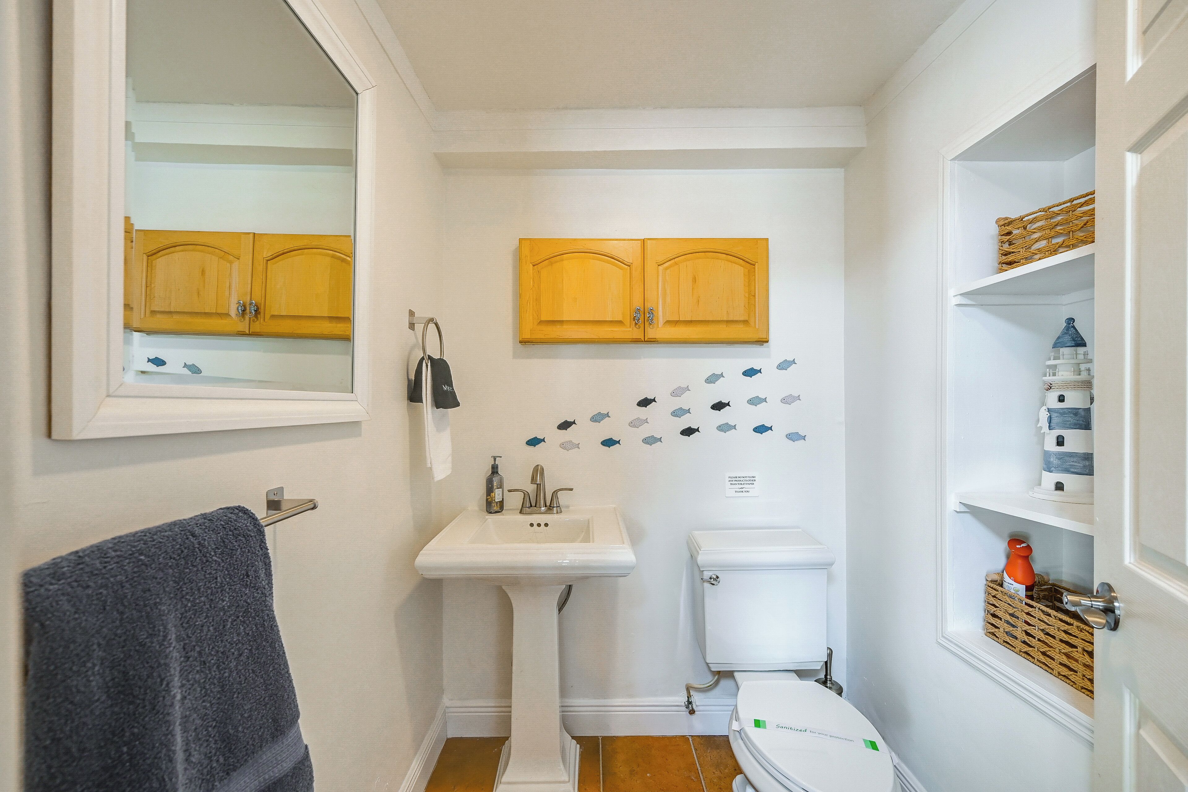A compact bathroom with a sink, toilet, and wooden cabinets above.