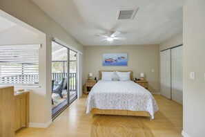 A bedroom with a bed, a ceiling fan, a painting, and a view through a glass door. - Island Oasis w/ Hot Tub, Walk to Shops and Dining (Marco Island)