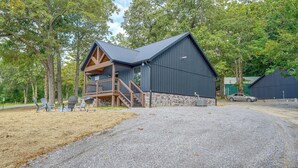 A rustic cabin with a wooden deck and a stone foundation, surrounded by trees. - Walk to the Water! Kentucky Lake Cabin (Murray)
