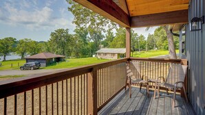 A wooden deck with a railing, overlooking a grassy area with a small cabin and a lake. - Walk to the Water! Kentucky Lake Cabin (Murray)