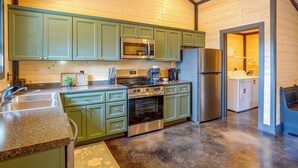 A kitchen with green cabinets, stainless steel appliances, and a granite countertop. - Walk to the Water! Kentucky Lake Cabin (Murray)
