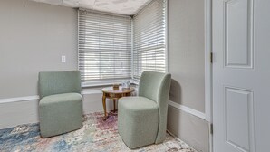 Ein Eckzimmer mit zwei Sesseln, einem kleinen Holztisch und einem gemusterten Teppich.