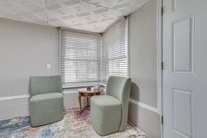 A corner room with two armchairs, a small wooden table, and a patterned rug.