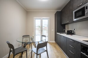Eine moderne Küche mit dunklen Schränken, einem Glastisch und Blick durch eine Glastür.
