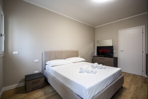 A bedroom with a bed, a TV, a nightstand, and a door. - Residenza Novoli Prestige - Free Private Parking (Firenze)