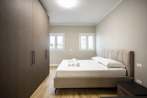 Een slaapkamer met een bed, een kledingkast en twee ramen.