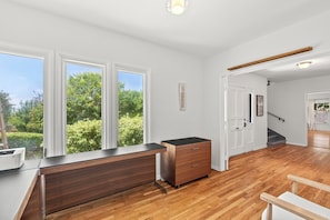 Une cuisine moderne dotée d’un plan de travail en bois, d’une cuisinière intégrée et offrant une vue sur la verdure grâce à de grandes fenêtres.