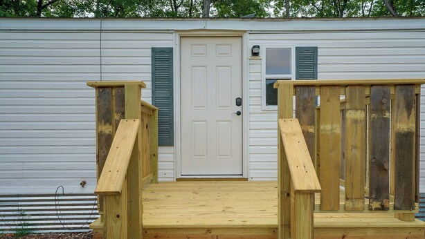 A wooden deck leading to a white door with a window and a doorbell. - Hot Tub + Dock! Lakefront Angler's Oasis in Irons (Irons)