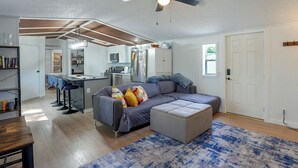 A modern living room with a sofa, ottoman, and a ceiling fan. - Hot Tub + Dock! Lakefront Angler's Oasis in Irons (Irons)