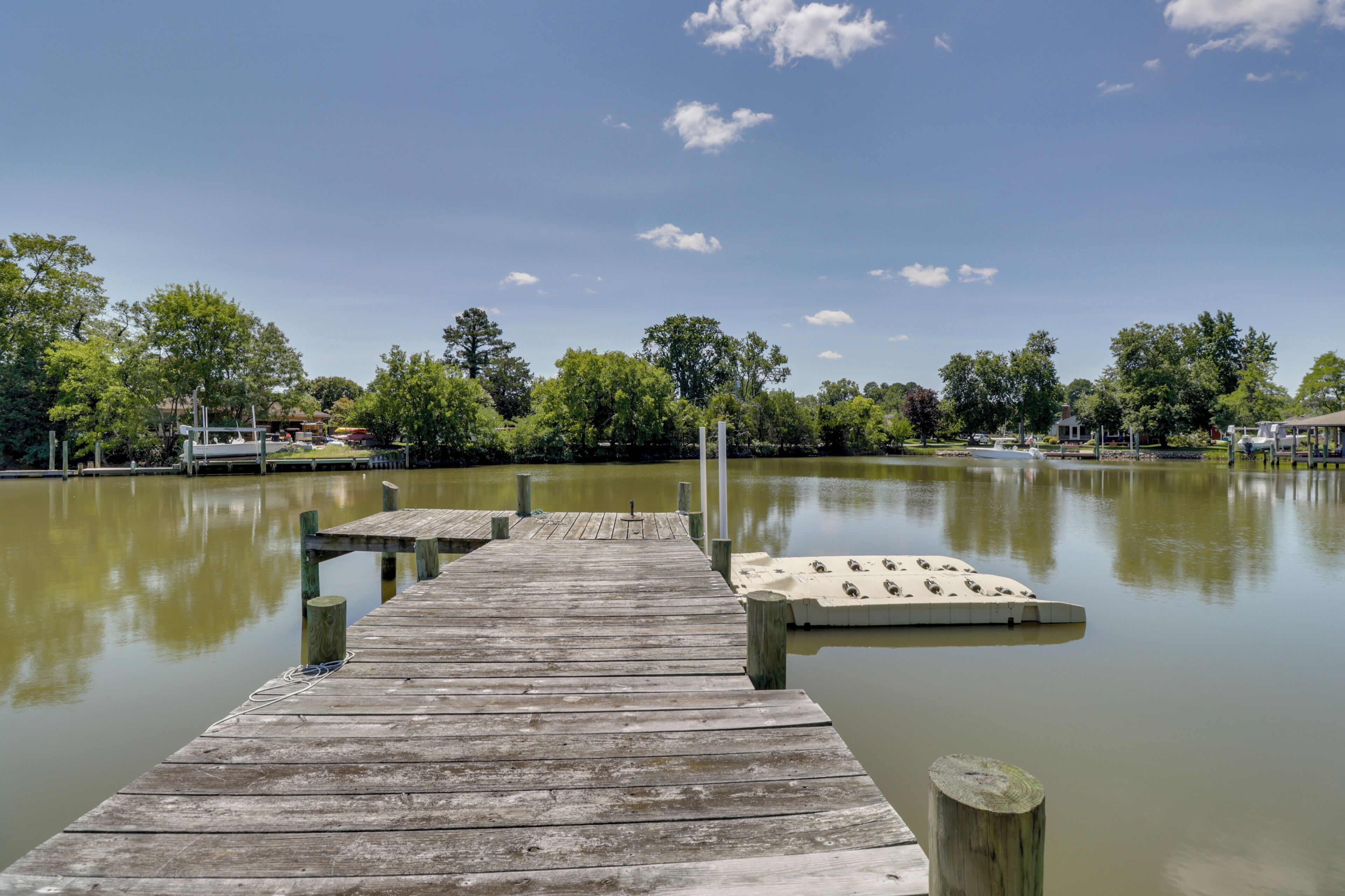 A wooden pier extending into a calm lake with a rowboat docked at the end.