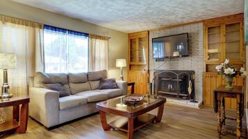 Una sala de estar con sofá, mesa de centro, chimenea, televisor y armarios de madera.