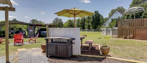 Patio trasero con una parrilla, mesa de picnic y zona de estar al aire libre.