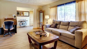 A living room with a sofa, a glass coffee table, a chair, a lamp, and a mirror. - Waterfront Family Home w/ Dock in Poquoson! (Poquoson)