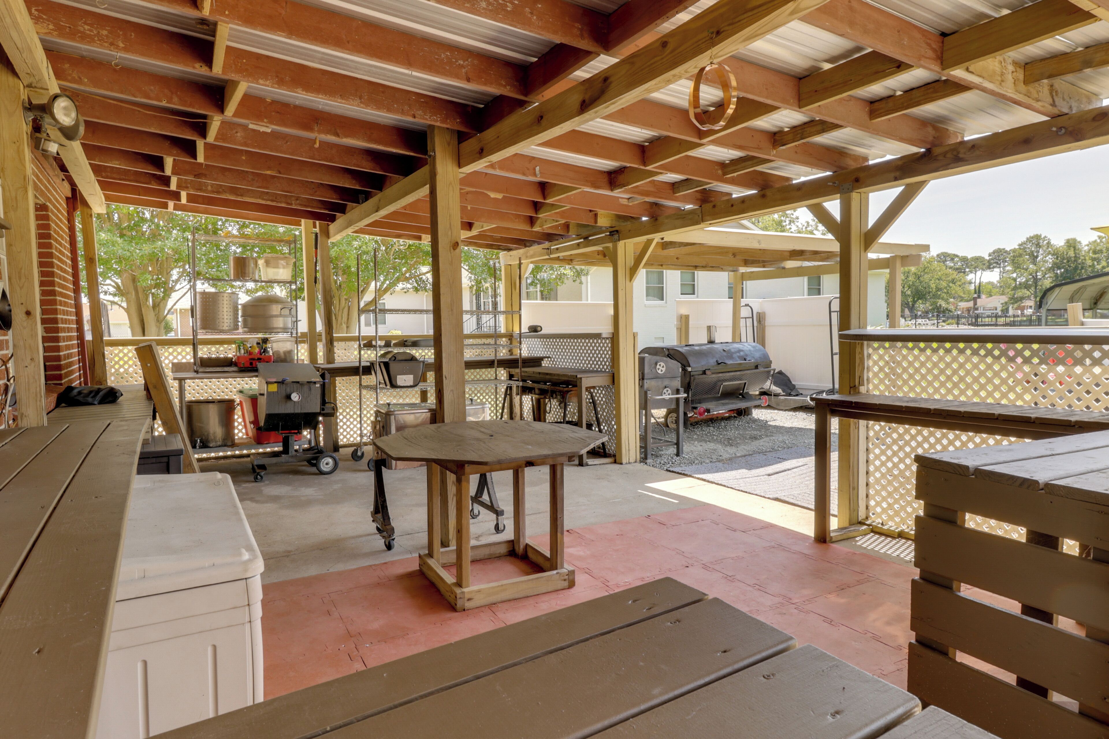 Une terrasse extérieure avec une table en bois, un gril et un barbecue.