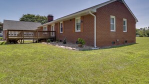 A two-story brick building with a covered deck and a grassy yard. - Waterfront Family Home w/ Dock in Poquoson! (Poquoson)