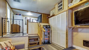 A compact living space with a kitchenette, a television mounted on the wall, and a staircase leading to an upper level. - Waterfront Family Home w/ Dock in Poquoson! (Poquoson)