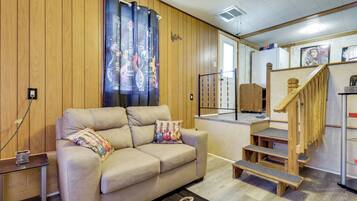Un espacio de sala acogedor con sofá, una mesa de centro y una escalera que lleva a un nivel superior.