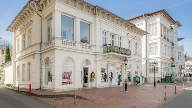 A historic building with large windows, a balcony, and a storefront with mannequins. - Villa Westfalia, Apartment 03, just 150 m from the beach, with shower - Modern vacation rental (Heringsdorf)