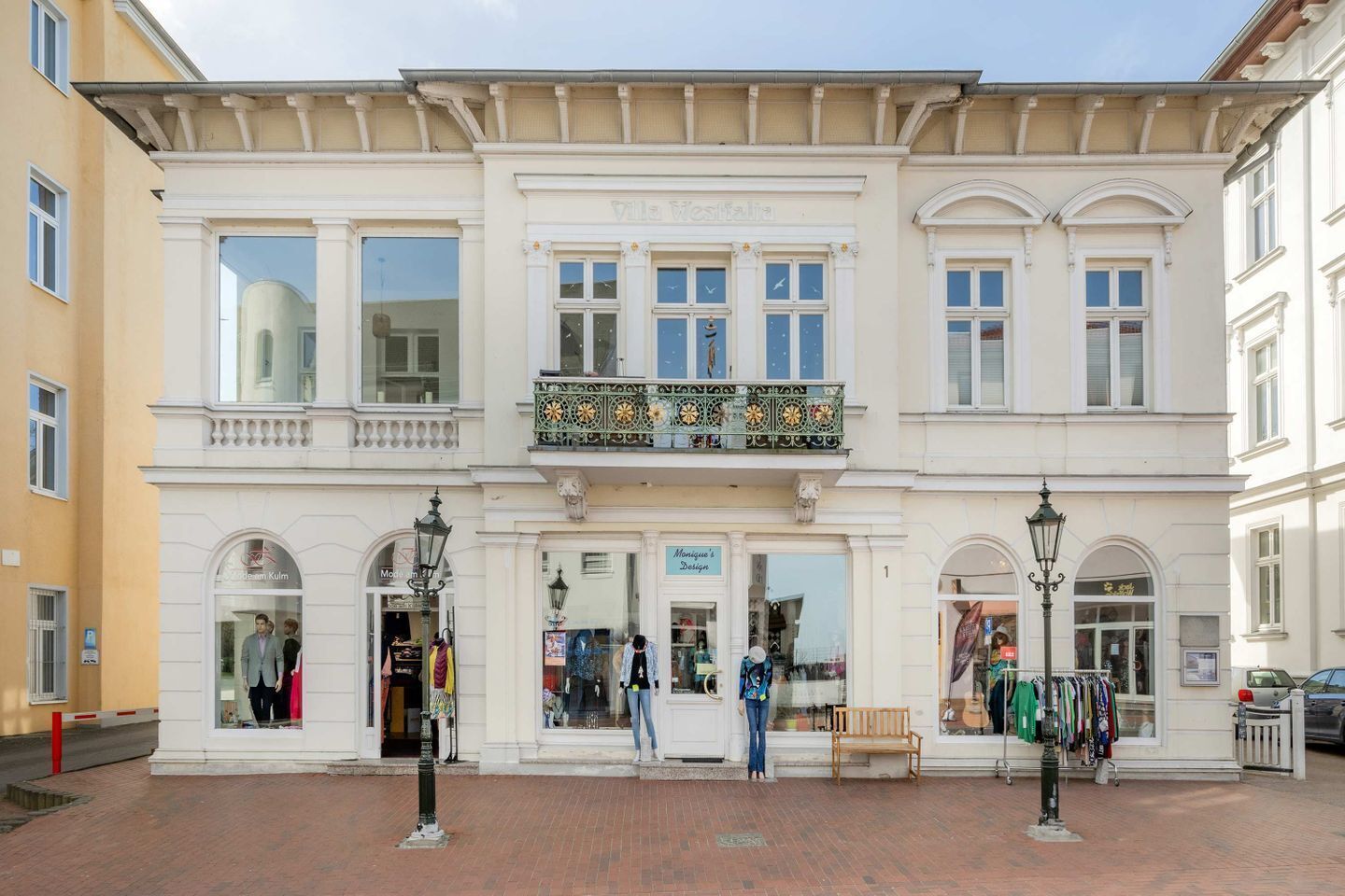 A historic building with a central entrance, two upper floors with balconies, and storefronts on the ground floor.