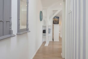 Ein Korridor mit Holzboden, weißen Wänden und einer Uhr an der Wand.