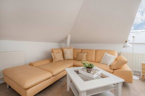 A modern living room with a beige sectional sofa, a white coffee table, and a potted plant. - Villa Westfalia, Apartment 02, with 2 bedrooms, just 150 m from the beach - Charming (Heringsdorf)