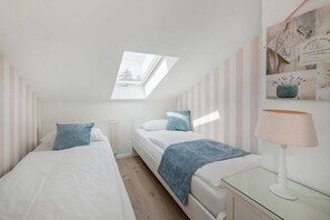 A bedroom with two beds, a skylight, a bedside lamp, and striped walls. - Villa Westfalia, Apartment 02, with 2 bedrooms, just 150 m from the beach - Charming (Heringsdorf)