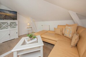 A cozy loft bedroom with a large window, a white cabinet, a beige sofa, and a small table with a plant. - Villa Westfalia, Apartment 02, with 2 bedrooms, just 150 m from the beach - Charming (Heringsdorf)