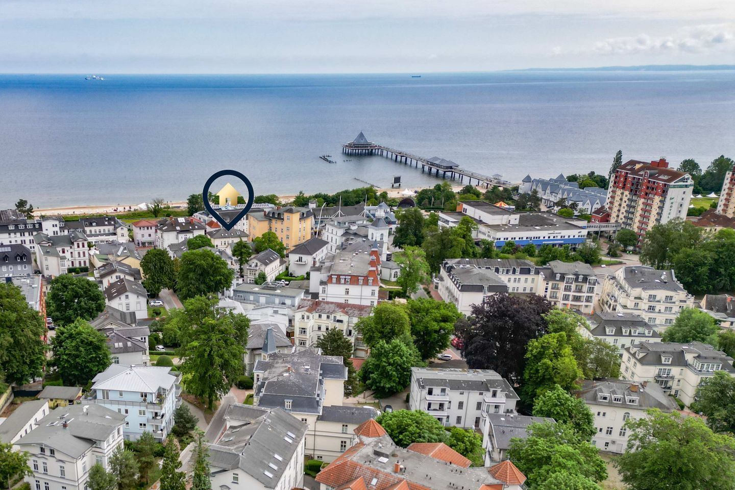 A coastal town with residential buildings, a pier, and a view of the sea.