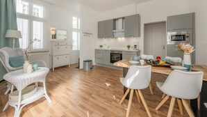 A modern kitchen with grey cabinets, a wooden dining table, and white chairs. - Villa Westfalia, Apartment 04, just 150 m from the beach, with a terrace - Cozy vacation rental in (Heringsdorf)
