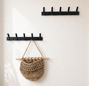 A wall-mounted black coat rack with hooks and a hanging woven bag. - Cabin 37 - Cabin 37 – Modern vacation home with a large balcony in Westerland (Sylt)