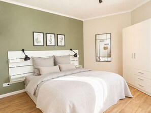 A bedroom with a white bed, green walls, and a white wardrobe. - Cabin 37 - Cabin 37 – Modern vacation home with a large balcony in Westerland (Sylt)