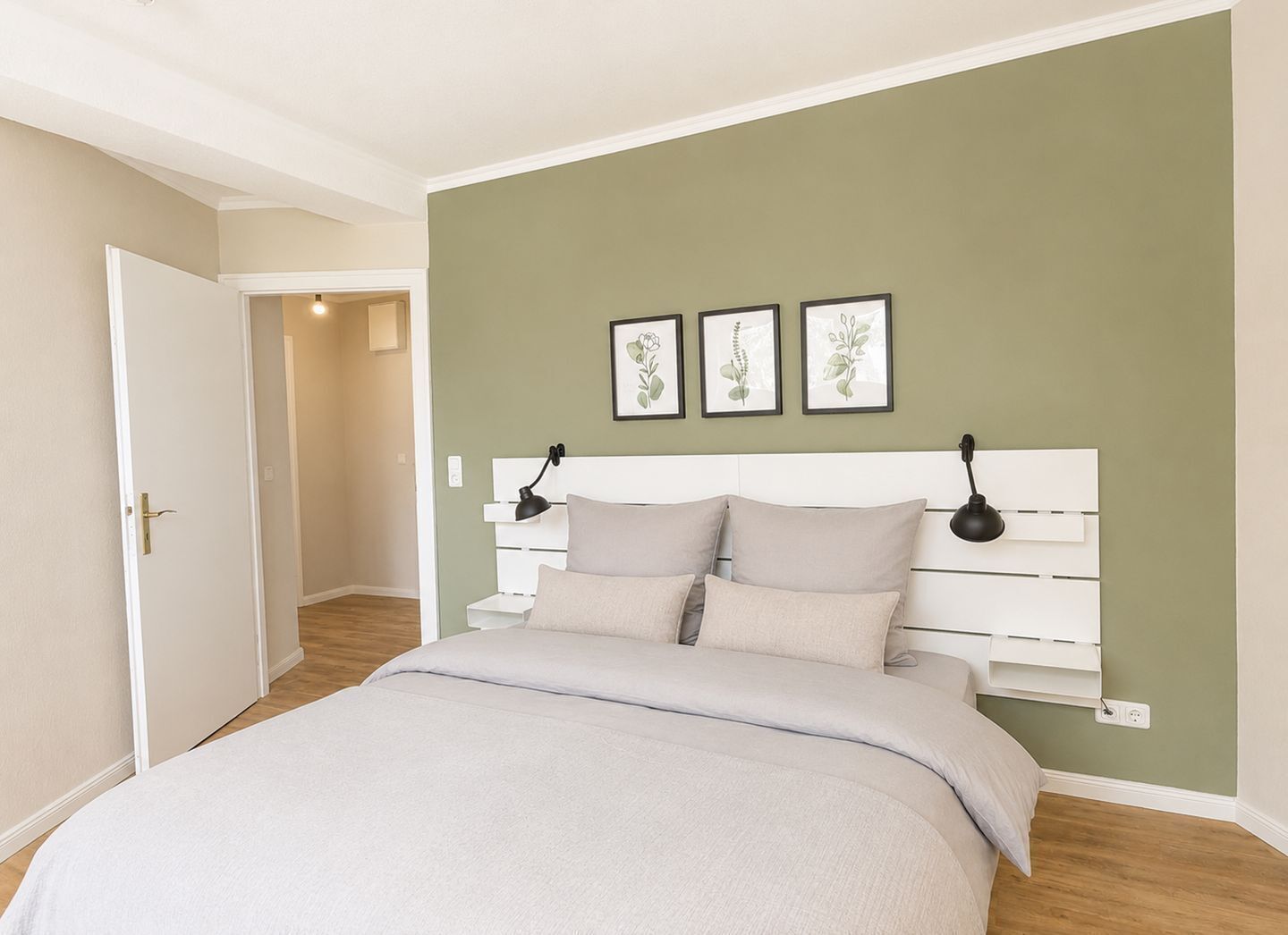 Ein Schlafzimmer mit einem Bett, zwei Nachttischlampen, einem weißen Kopfende und einer grünen Wand.