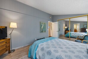 A hotel room with a bed, a desk, a lamp, a television, and a mirror. - Monarch Pines - Pacific Grove Home - Over 55 Park - Steps to the Sand! (Pacific Grove)