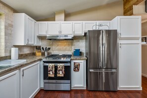 A kitchen with white cabinets, stainless steel appliances, a gas stove, and a refrigerator. - Monarch Pines - Pacific Grove Home - Over 55 Park - Steps to the Sand! (Pacific Grove)