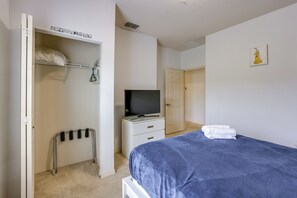Une chambre à coucher avec un lit, un téléviseur posé sur un meuble, une armoire et une porte.