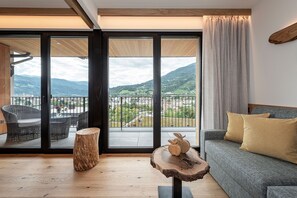 Een moderne woonkamer met een balkon, houten vloeren en uitzicht op het landschap.