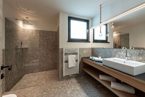 Een moderne badkamer met een douche in glazen cabine, een grote spiegel en een wastafelmeubel met twee wastafels.