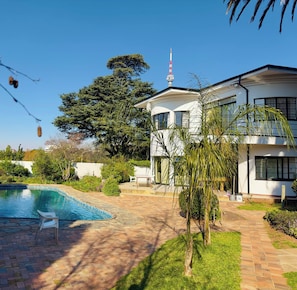 A two-story house with a swimming pool, surrounded by greenery and a clear sky. - Single Room with Shared Bathroom 1 (Johannesburg)