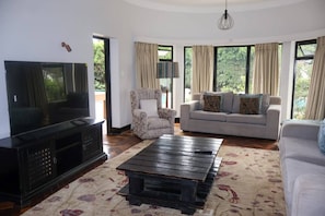 A living room with a television, two sofas, a patterned rug, and large windows. - Single Self-Contained Rooms (Johannesburg)