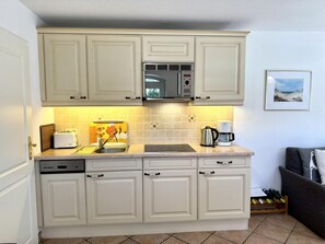 Eine Küche mit weißen Schränken, einer Mikrowelle, einem Toaster und einer Kaffeemaschine.