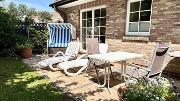 A patio with a table and chairs, a striped beach chair, and a potted plant.